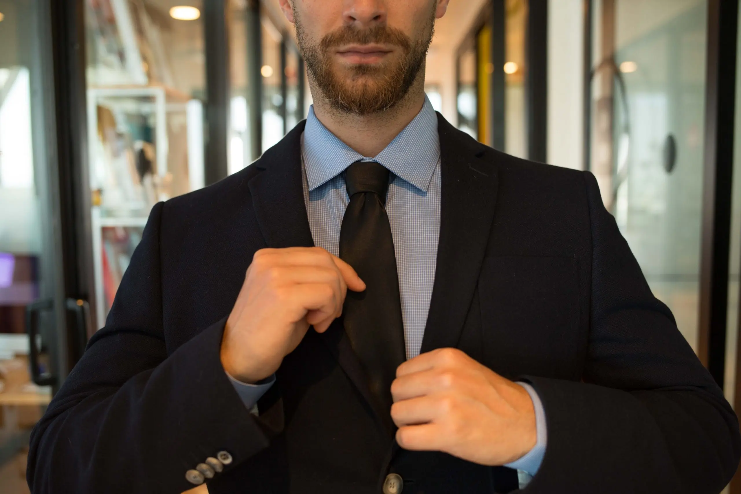 Un hombre de traje con una camisa azul que dice 'corbata negra